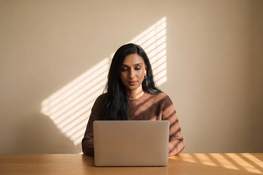 A woman reading at a laptop at a wooden table